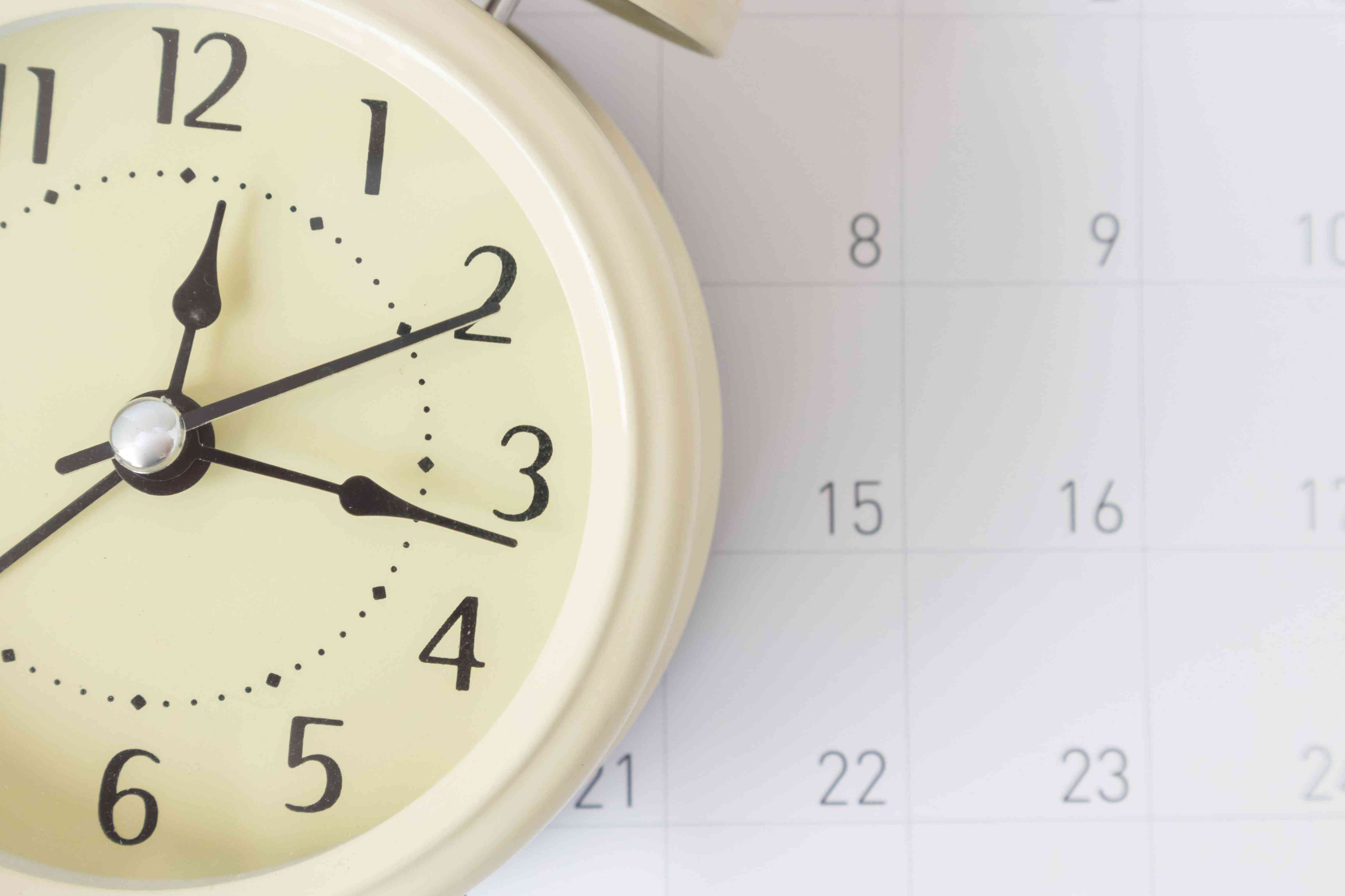 Close-up of clock against calendar