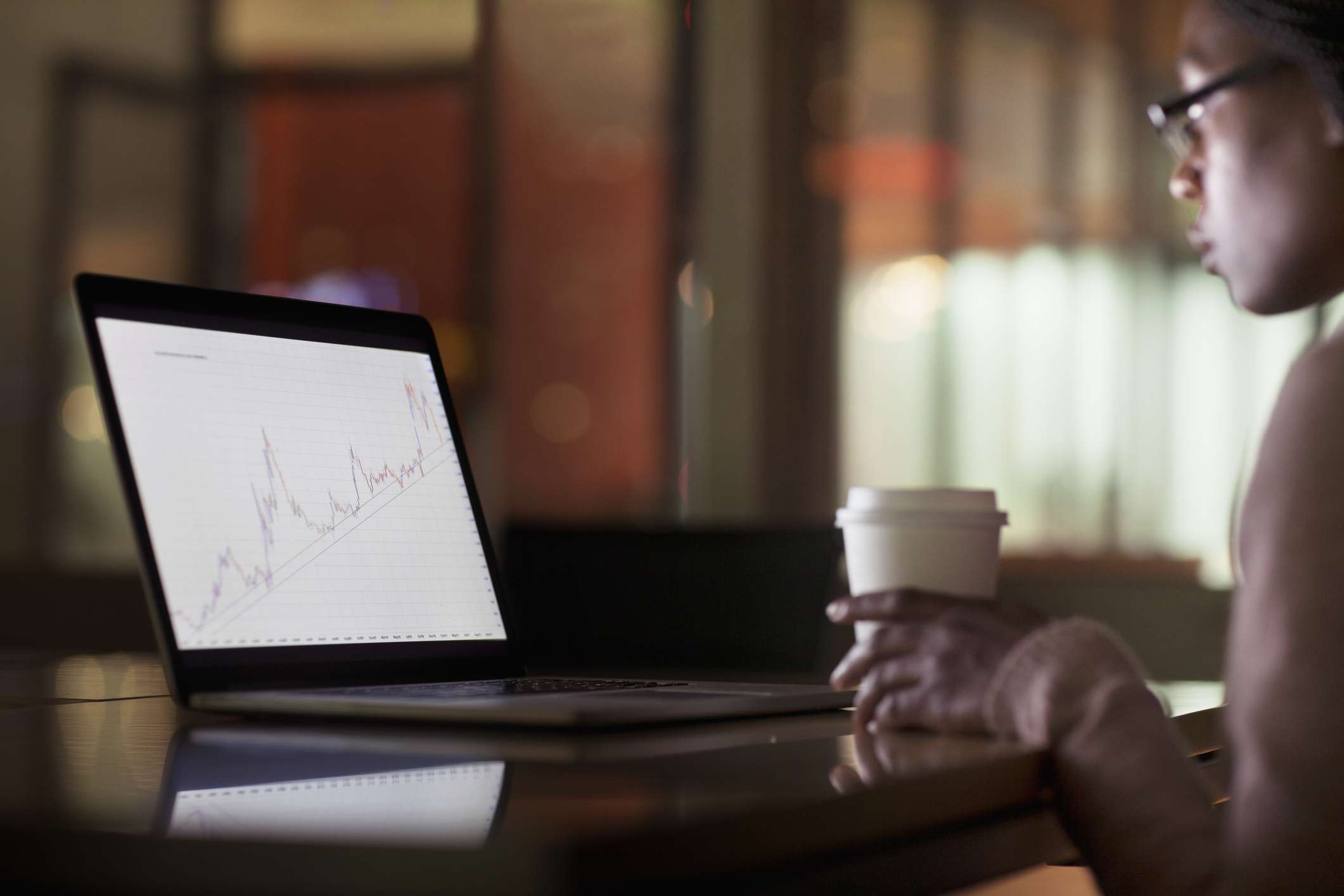 A woman viewing laptop screen with graph diagram.