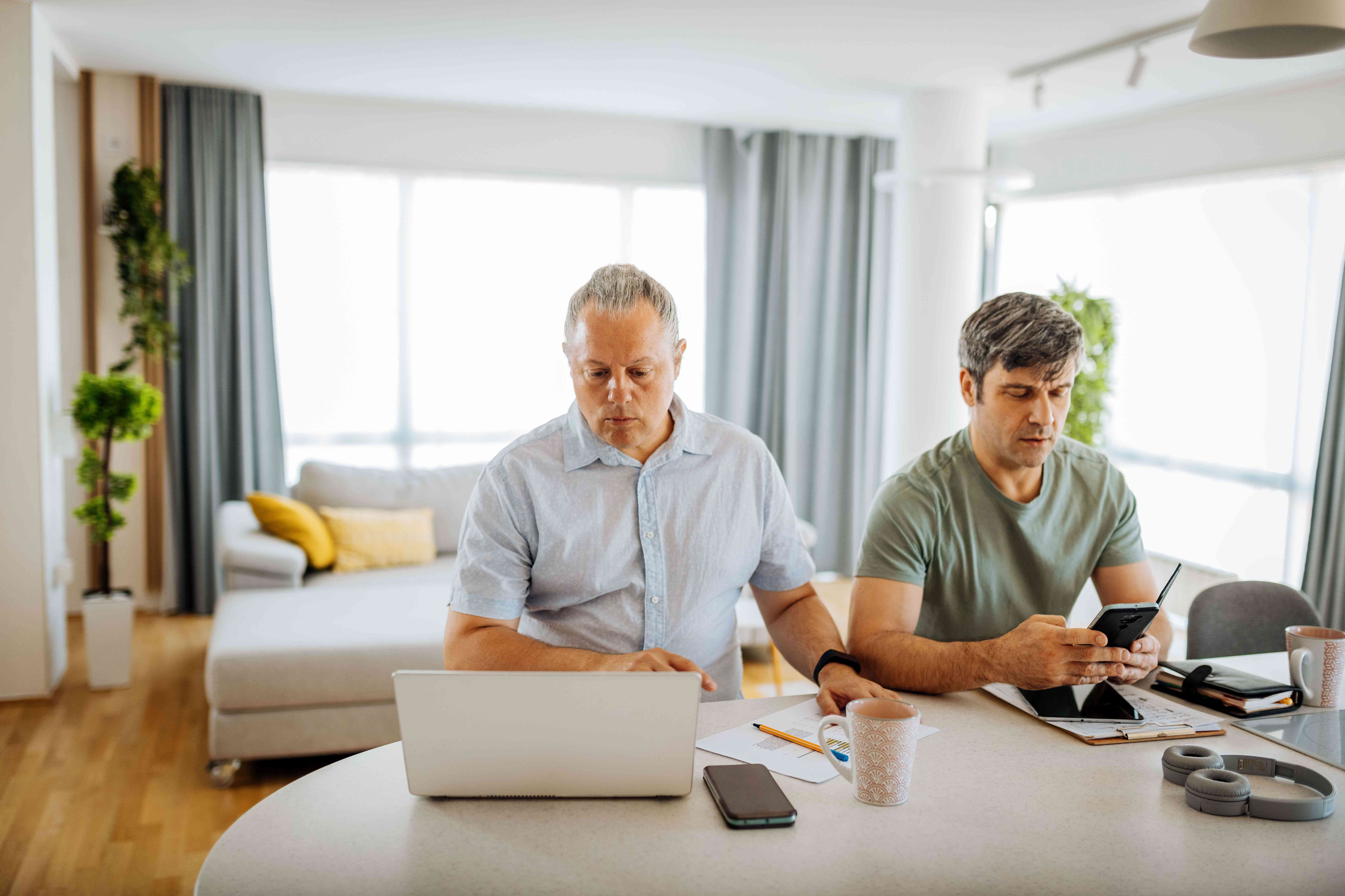 Two men working on devices at home