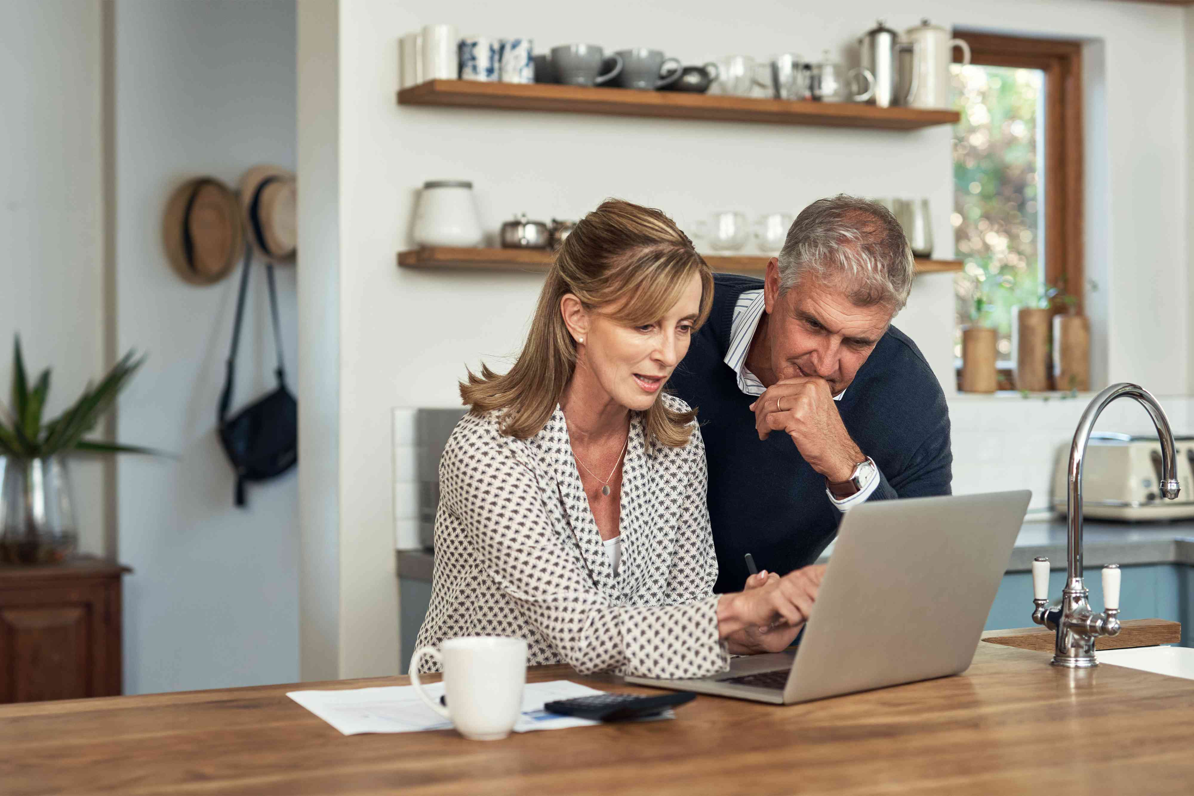 A senior couple planning their finance and paying bills while using a laptop at home