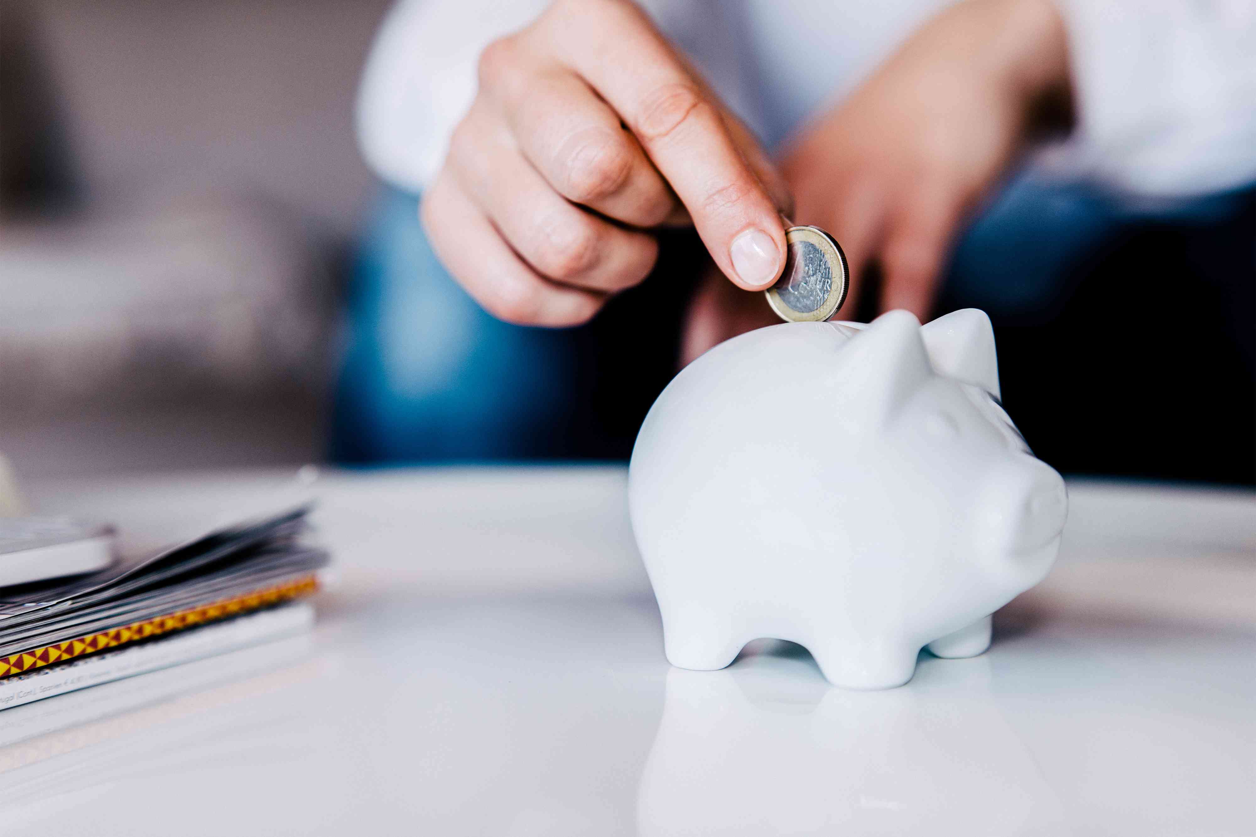 Putting a coin in a white piggy bank at home savings account concept