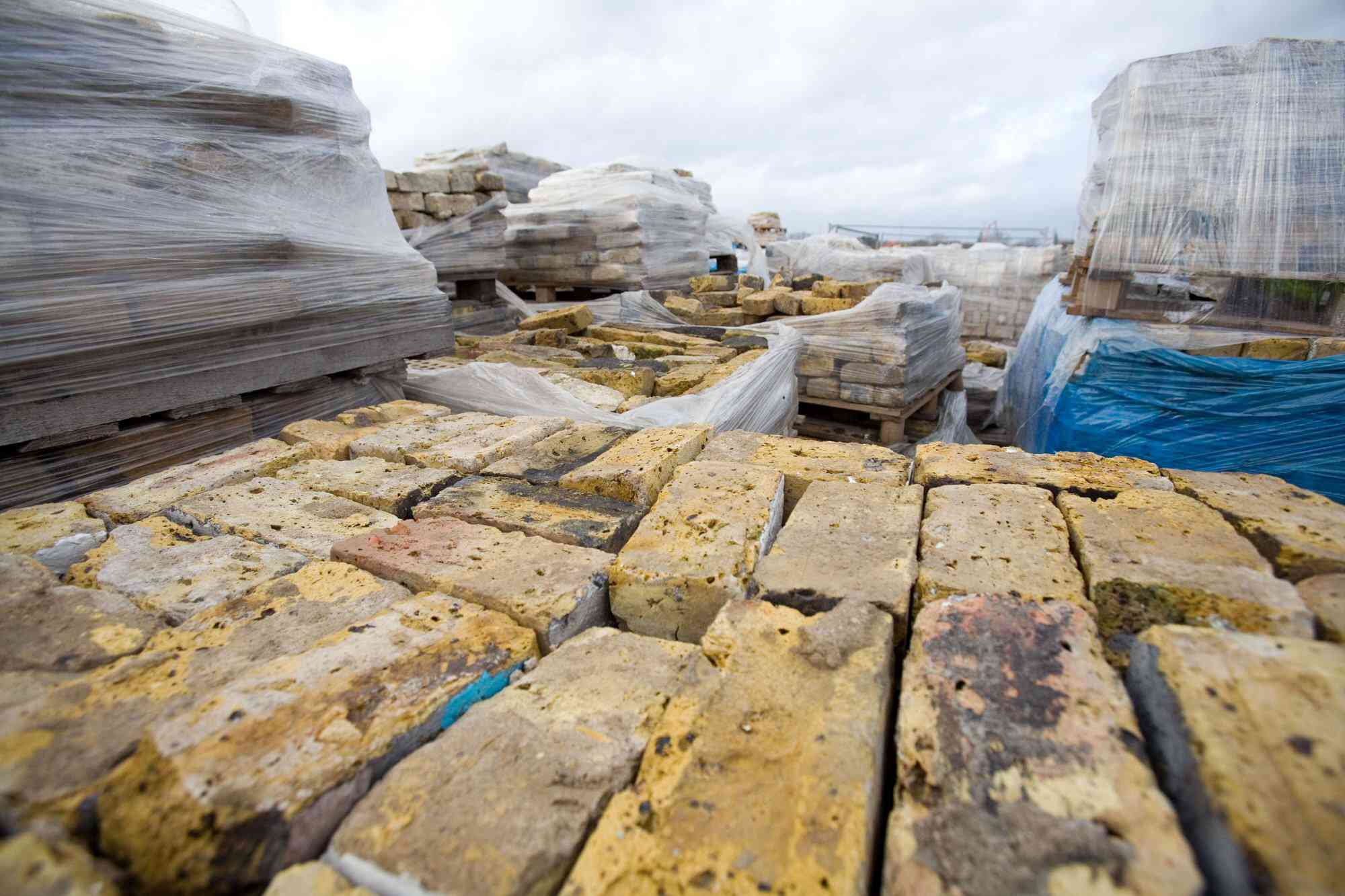 Photo of reclaimed stone bricks and stacked lumber ready to be reused in construction projects.
